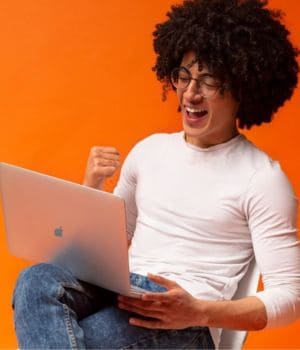 man with laptop sitting on a chair giving victory sign